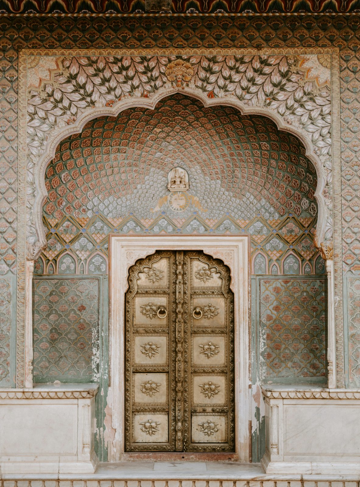 Ornate brass door set in a decorated arched niche with floral patterns, Jaipur
